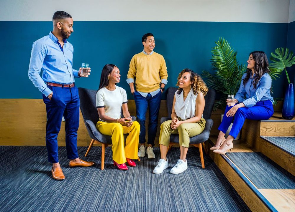 A diverse group of friends talking and laughing together on lounge seating