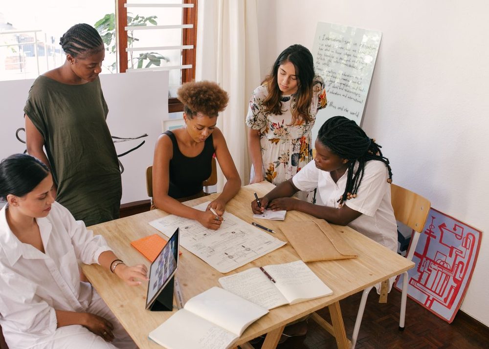 A group of friends planning together around a table with notes and a tablet